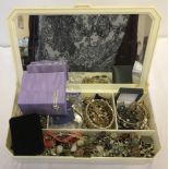 A cream jewellery box containing quantity of costume jewellery.