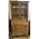 A pine bureau bookcase with 2 door glass cupboard above.