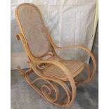 A light wood rocking chair with cane seat and back.