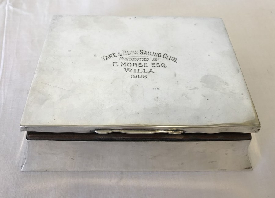 A silver lined cigarette box with shaped base. Engraved on lid.