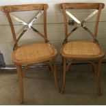 A pair of modern natural oak dining chairs.