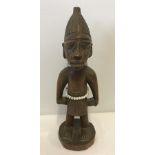 A carved wooden Tribal figure, from The Ivory Coast, of a man wearing beads.