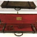 An antique leather gun case with brass corners and leather straps.