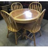 A light wood circular extending kitchen table with terracotta coloured tiled top & 4 chairs.