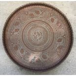 A large copper tray with pie crust edge and bird and leaf decoration.