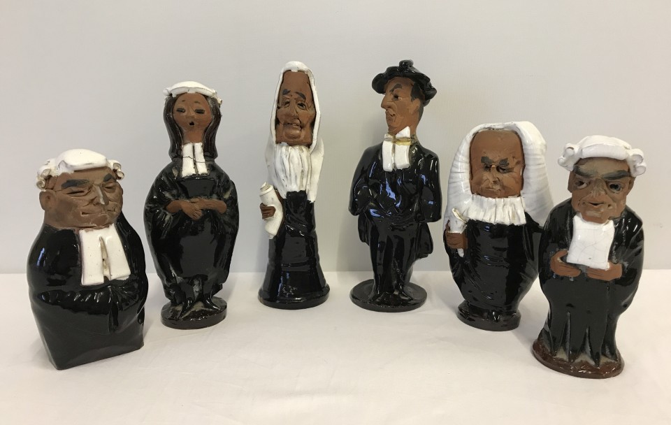 A collection of 6 pottery figurines of judges, lawyers and barristers.