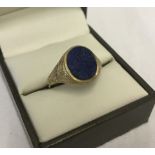 A hallmarked 9ct gold gents signet ring set with oval Lapis stone and decoration to shoulders.