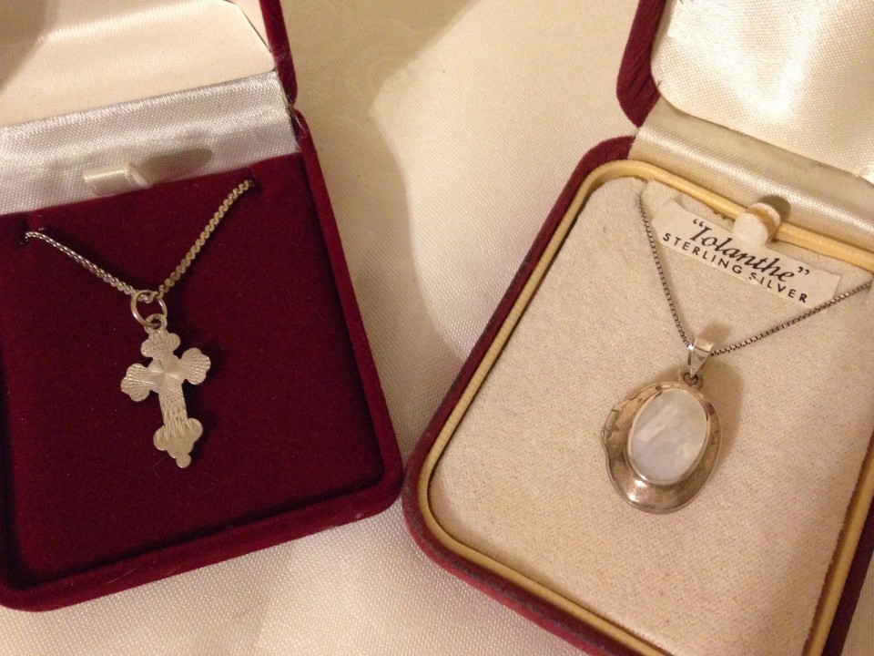 An oval silver locket set with mother of pearl, together with a silver cross - both on silver chains