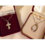 An oval silver locket set with mother of pearl, together with a silver cross - both on silver chains