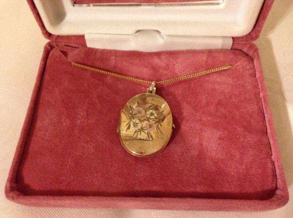 A 9ct gold oval locket with floral decoration, on a 9ct gold chain.