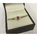 A fully hallmarked 9ct gold dress ring set with central oval ruby with a small diamond either side.