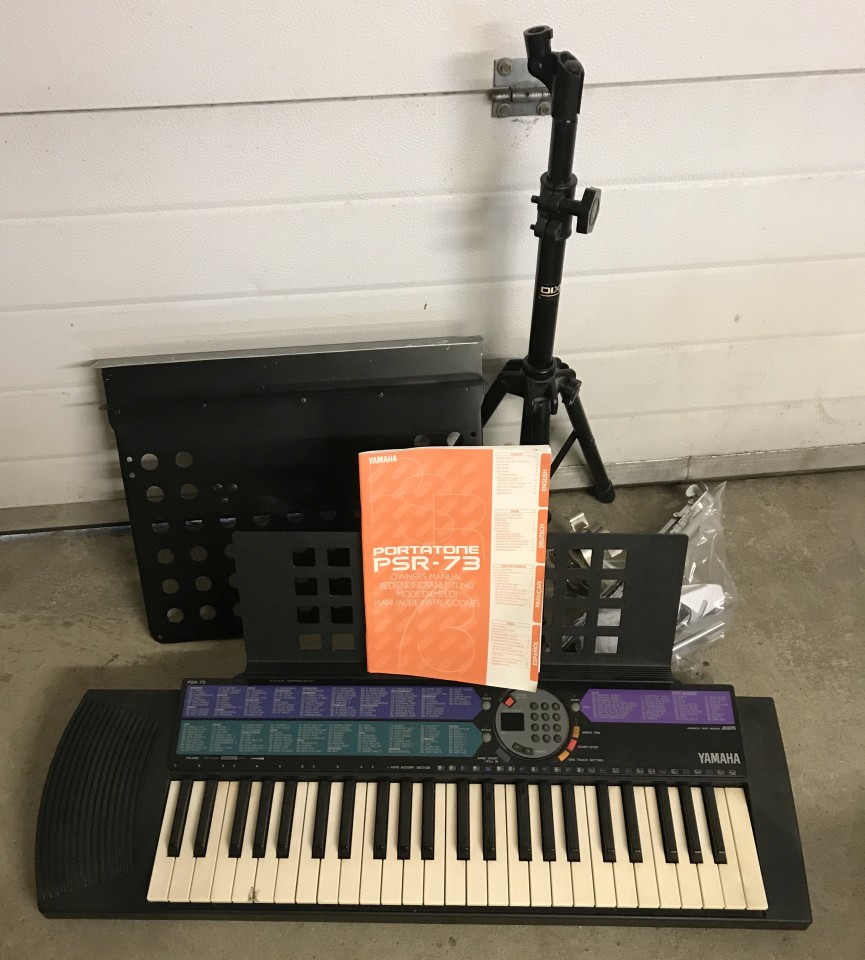 A Yamaha Portatone PSR-73 electronic keyboard with power adapter and instruction manual.