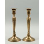 A pair of George III bell metal candlesticks with fluted tapering columns, circular step bases