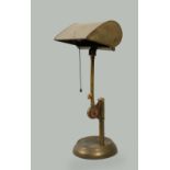 An early 20c brass desk lamp, adjustable and with shades, supported on a circular dished base, 18h.