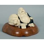 A Meiji period carved ivory figure of Hotei seated alongside a knotted bag and a small table on