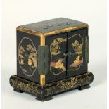 A Japanese Meiji period black lacquered shibiyama decorated miniature three drawer cabinet on stand,