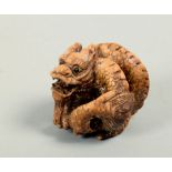 An Oriental carved wooden boxwood netsuke in the form of a coiled dragon, carved mono ECH, 1.75w.