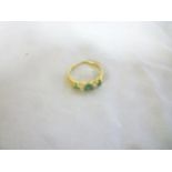 A gold dress ring set three green stones