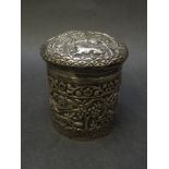 A white metal embossed lidded canister, lions, elephants, rabbits, palm trees etc,