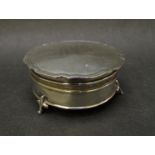 A silver circular footed trinket box, raised on three feet, Birmingham 1921, monogrammed,