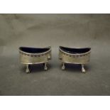 A pair of silver pierced and engraved salts, raised on four ball and claw feet, blue glass liners,