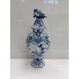A Delft blue and white vase, the lid surmounted by a bird,