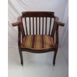 An Arts and Crafts mahogany desk chair the low back and outswept arms over a serpentine front seat