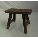 An 18th Century elm milking stool with exposed joints,