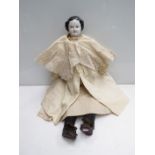 A 20" tall mid 19th Century glazed porcelain head doll, wearing white dress and black shoes,