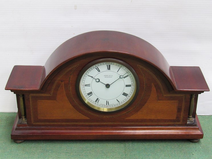 An Edwardian mahogany and inlaid mantel clock with brass bezel, bun feet and spindle columns,