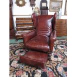 A Victorian brown leather upholstered wing-back gout chair with ratcheted foot stool