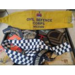 A collection of military cloth and metal insignia including Civil Defence Corps Welfare arm band,