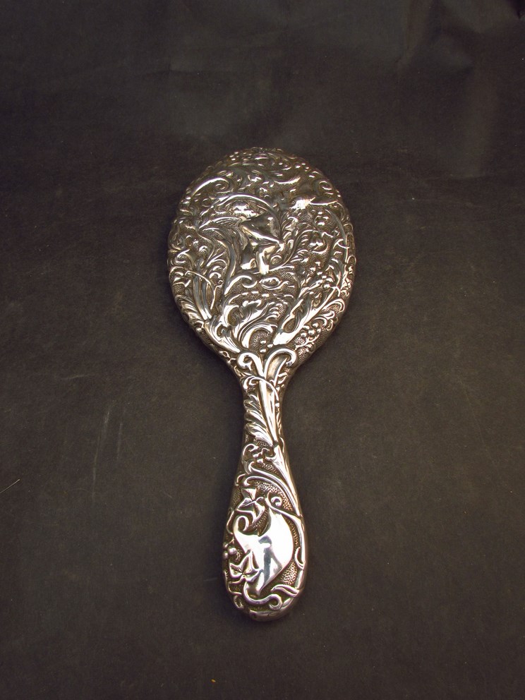 A silver embossed hand mirror with bug, foliate and figural design,