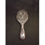 A silver embossed hand mirror with bug, foliate and figural design,