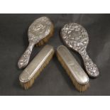 Four silver backed dressing table items including embossed hand mirror