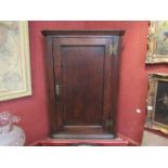 A 19th Century oak single door corner cupboard with decorative brass butterfly hinges and key