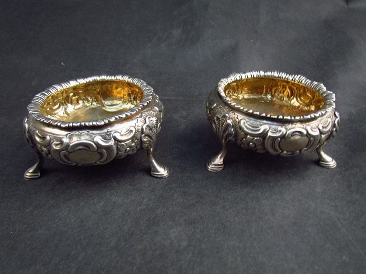 A pair of Robert Death silver salts, gilt bowls with embossed bodies raised on shell and hoof feet,