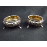 A pair of Robert Death silver salts, gilt bowls with embossed bodies raised on shell and hoof feet,