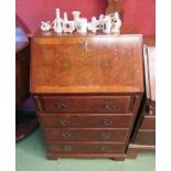 A walnut bureau with four graduating drawers,