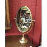 A brass oval dressing table mirror