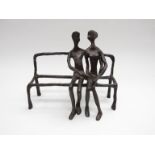 A contemporary bronzed Giacometti style couple on a bench.