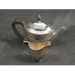 A silver two piece teaset with melon fluted body, treen finial and handle, Sheffield marks rubbed,