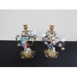 A pair of ormolu candlestick depicting shepherd and shepherdess and decorated with porcelain flower