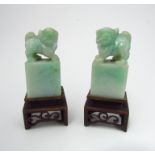 A pair of carved jade Dogs of Fo seals on carved wooden stands