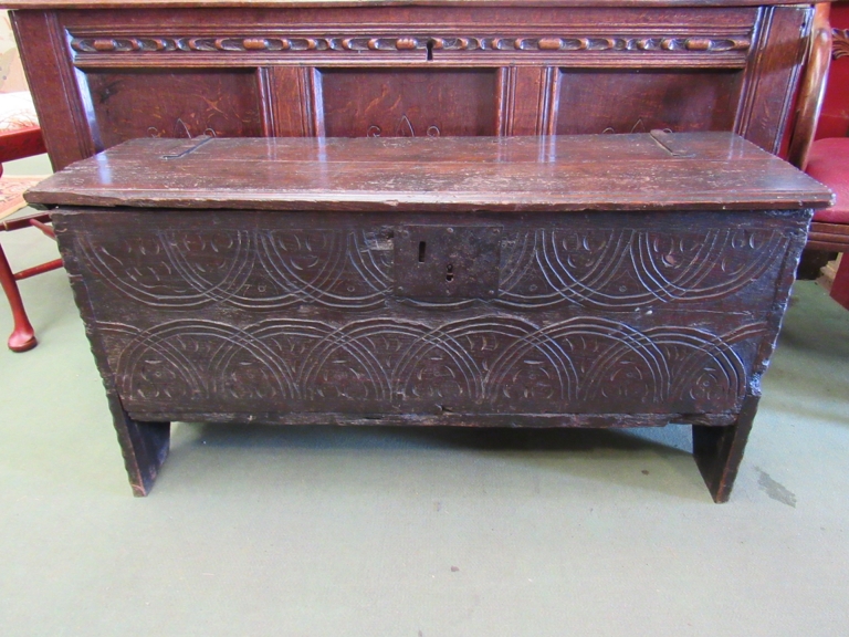 A 17th Century six plank oak coffer with carved lunette frieze, top split,