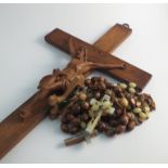 A wooden crucifix with Christ on the cross and a collection of Rosary bead necklaces with cross