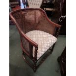 An Edwardian bergere armchair on barley twist arm supports and turned legs with barley twist