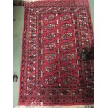 A red ground rug with geometric design and tasselled ends,