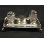 A silver desk stand with twin silver mounted inkwell and central lidded pot with military insignia