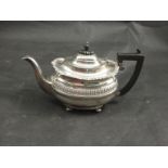 A silver teapot with ebony finial and handle fluted band to body, raised on four feet,